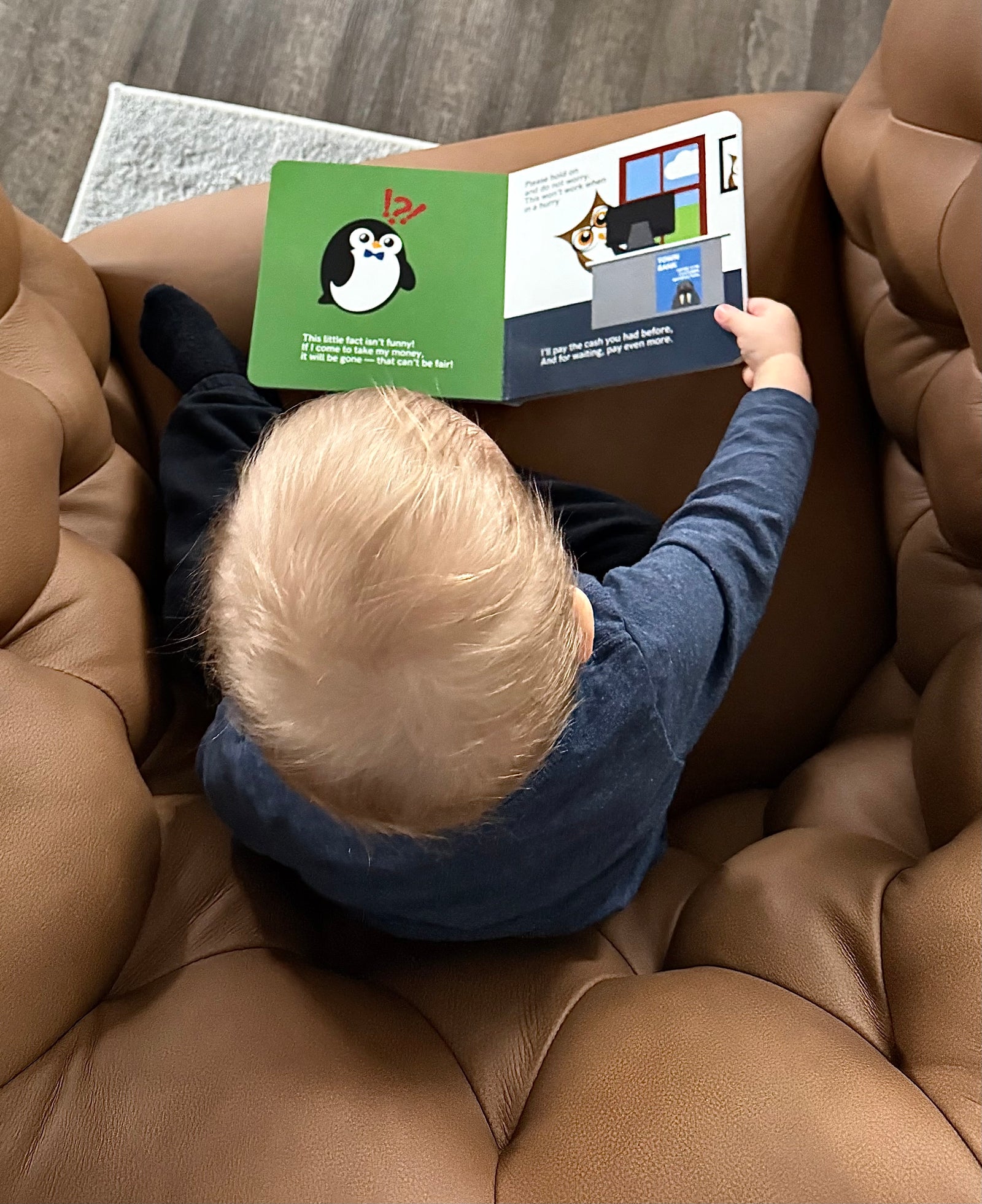 Child reading a books about money and banking on a brown couch. Showing that teaching kids about money doesn’t have to be complicated.